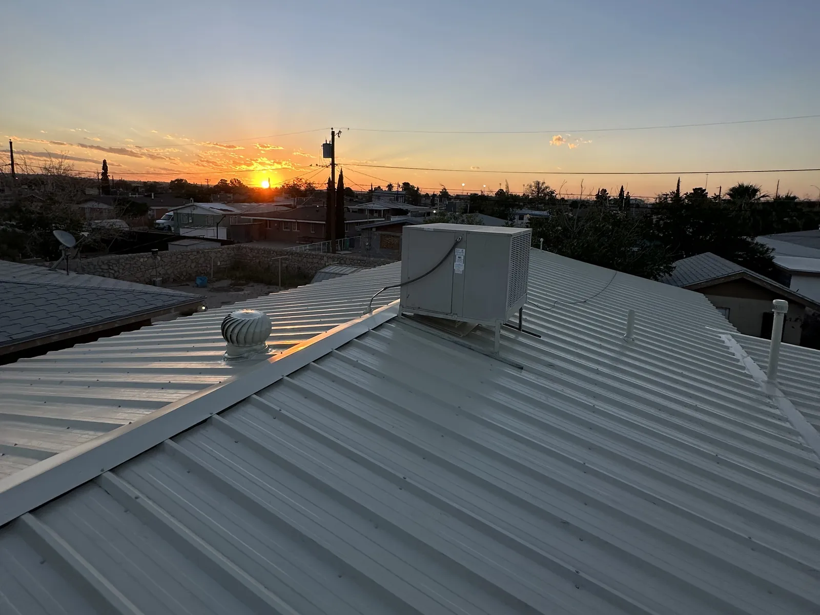 The finished Light Stone R-panel roof at sunset, with the same turbine vent and cooler
