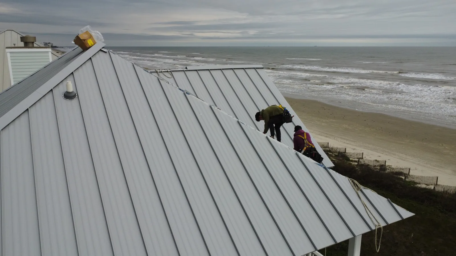Our crew installing a standing seam roof on a beachfront home